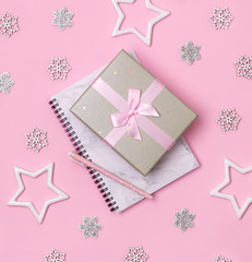Christmas winter celebration concept. Marble notepad with pen and gift on pink background