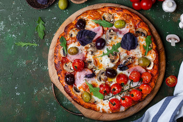 Delicious fresh pizza with ham, mushrooms and tomatoes