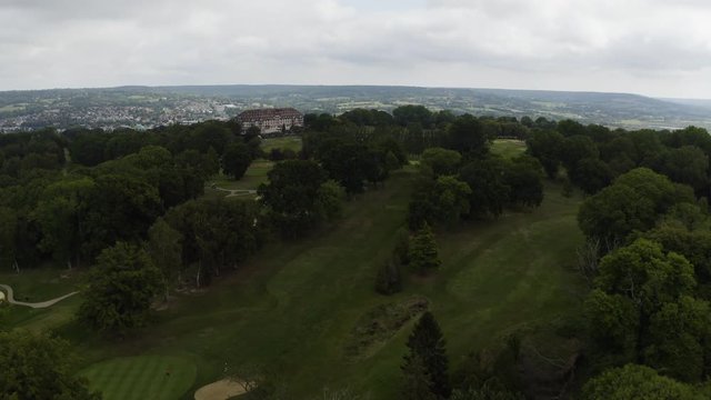 Aerial Drone Footage of golf trees forest over summer mountains, hills and meadows with forests in sun soft light with cloudy blue sky over mountain. Deauville, France. 4K UHD. Golfing, rich house.