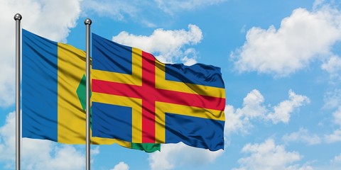 Saint Vincent And The Grenadines and Aland Islands flag waving in the wind against white cloudy...