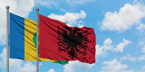 Saint Vincent And The Grenadines and Albania flag waving in the wind against white cloudy blue sky...