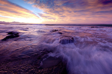 The waves at high tide overflow the rocky beach