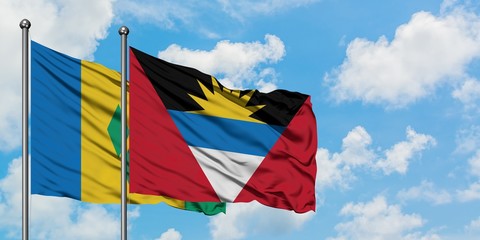 Saint Vincent And The Grenadines and Antigua and Barbuda flag waving in the wind against white cloudy blue sky together. Diplomacy concept, international relations.