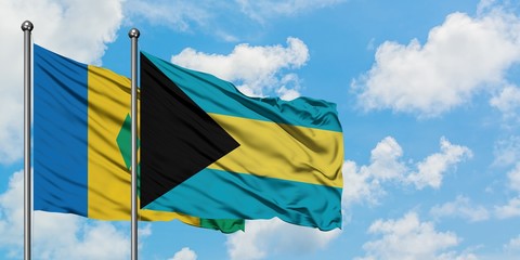 Saint Vincent And The Grenadines and Bahamas flag waving in the wind against white cloudy blue sky together. Diplomacy concept, international relations.