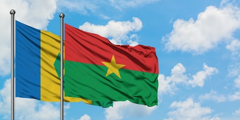 Saint Vincent And The Grenadines and Burkina Faso flag waving in the wind against white cloudy blue...