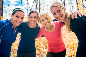 woman group out running together in an autumn park they run a race or train in a healthy outdoors lifestyle concept