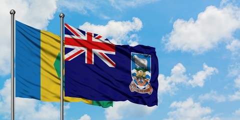 Saint Vincent And The Grenadines and Falkland Islands flag waving in the wind against white cloudy...