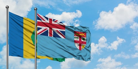 Saint Vincent And The Grenadines and Fiji flag waving in the wind against white cloudy blue sky together. Diplomacy concept, international relations.