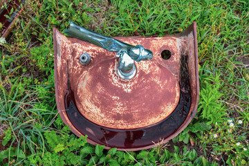 One of a  junkyard collection of rusting sinks seen turned upside down, this discarded fixture...