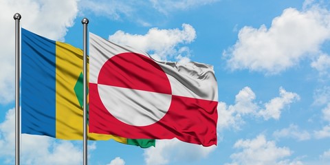 Saint Vincent And The Grenadines and Greenland flag waving in the wind against white cloudy blue...