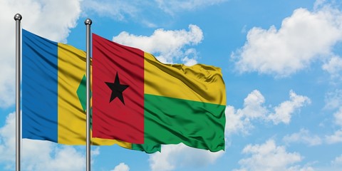 Saint Vincent And The Grenadines and Guinea Bissau flag waving in the wind against white cloudy...
