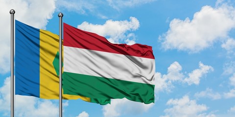 Saint Vincent And The Grenadines and Hungary flag waving in the wind against white cloudy blue sky...