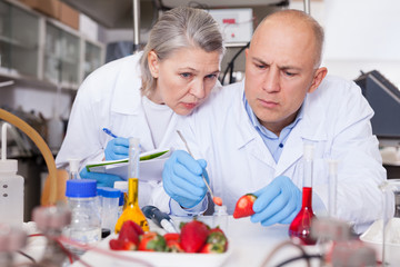 Scientists taking notes while performing experiments