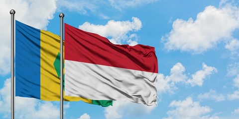 Saint Vincent And The Grenadines and Indonesia flag waving in the wind against white cloudy blue sky together. Diplomacy concept, international relations.