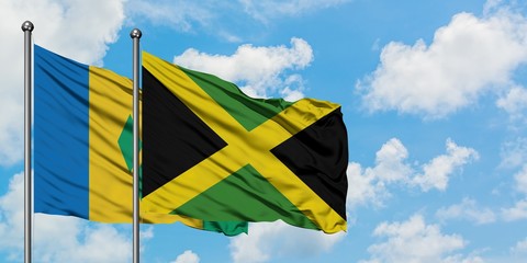 Saint Vincent And The Grenadines and Jamaica flag waving in the wind against white cloudy blue sky together. Diplomacy concept, international relations.