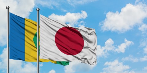 Saint Vincent And The Grenadines and Japan flag waving in the wind against white cloudy blue sky...