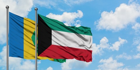 Saint Vincent And The Grenadines and Kuwait flag waving in the wind against white cloudy blue sky...
