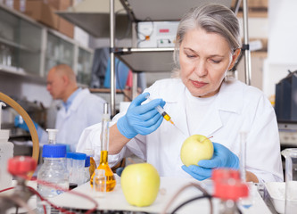 Female scientist injecting reagent into apple