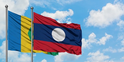 Saint Vincent And The Grenadines and Laos flag waving in the wind against white cloudy blue sky together. Diplomacy concept, international relations.