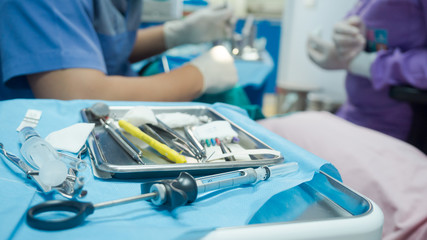 Selective focus dental equipment for dentist and blurry dentist examining patient tooth on dental chair at dental department.Medical mouth and tooth health care concept.