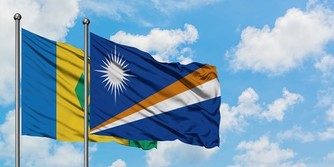 Saint Vincent And The Grenadines and Marshall Islands flag waving in the wind against white cloudy blue sky together. Diplomacy concept, international relations.