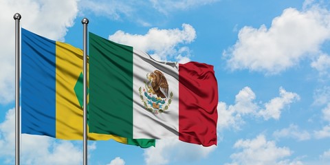 Saint Vincent And The Grenadines and Mexico flag waving in the wind against white cloudy blue sky...