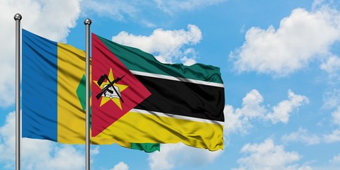 Saint Vincent And The Grenadines and Mozambique flag waving in the wind against white cloudy blue...