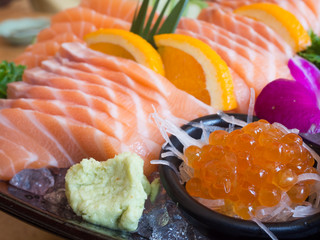 Big set of sushi on a wooden table in a Japanese restaurant.Fresh salmon sliced for sushi menu.