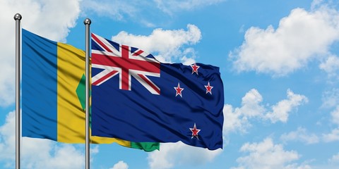 Saint Vincent And The Grenadines and New Zealand flag waving in the wind against white cloudy blue...