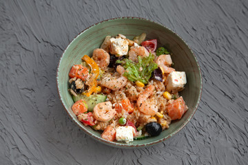 Mediterranean dish, rice with seafood, vegetables, olives, feta. Top view. Plate on a gray background.