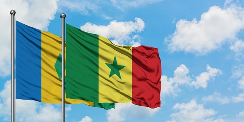 Saint Vincent And The Grenadines and Senegal flag waving in the wind against white cloudy blue sky...