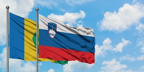 Saint Vincent And The Grenadines and Slovenia flag waving in the wind against white cloudy blue sky...