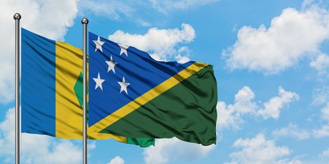 Saint Vincent And The Grenadines and Solomon Islands flag waving in the wind against white cloudy blue sky together. Diplomacy concept, international relations.