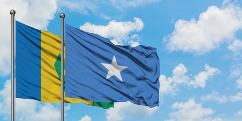 Saint Vincent And The Grenadines and Somalia flag waving in the wind against white cloudy blue sky together. Diplomacy concept, international relations.