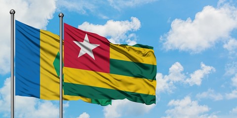 Saint Vincent And The Grenadines and Togo flag waving in the wind against white cloudy blue sky together. Diplomacy concept, international relations.