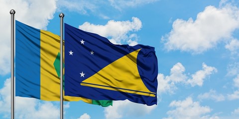 Saint Vincent And The Grenadines and Tokelau flag waving in the wind against white cloudy blue sky...