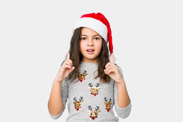 Little girl celebrating christmas day pointing upside with opened mouth.