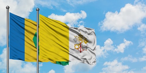 Saint Vincent And The Grenadines and Vatican City flag waving in the wind against white cloudy blue...