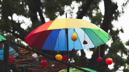 Fototapeta na wymiar colorful umbrella in the park with colorful balls and bokeh tree