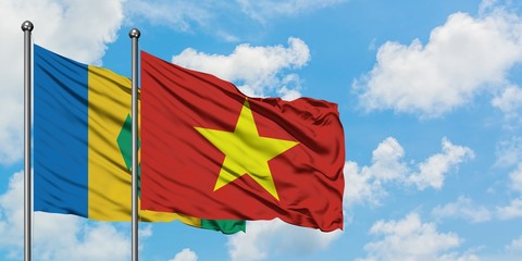 Saint Vincent And The Grenadines and Vietnam flag waving in the wind against white cloudy blue sky...