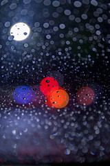 Multicolored, blurry bokeh balls behind a windshield on a rainy night in New York City