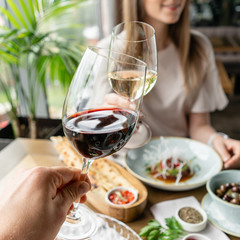 Date, man and woman Clink wine glasses. Beautiful young elegant woman in the restaurant with a wine glass. Dinner and a variety of dishes on the table. Italian cuisine