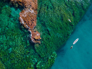 Aerial view of a paddle board in the water floating on a transparent sea, snorkeling. Bathers at sea. Tropea, Calabria, Italy. Diving relaxation and summer vacations. Italian coasts, beaches and rocks © Naeblys