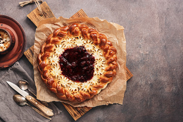 Sweet pie with cottage cheese with strawberry jam, a cup of hot coffee, rustic dark background. Top view, flat lay, copy space.