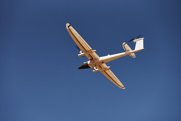 Modern small remote controlled white colored plane flying up in the sky
