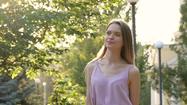 Beautiful young woman in park on sunny day. Slow motion effect
