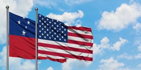 Obraz premium Samoa and United States flag waving in the wind against white cloudy blue sky together. Diplomacy concept, international relations.