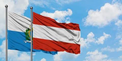 San Marino and Austria flag waving in the wind against white cloudy blue sky together. Diplomacy concept, international relations.