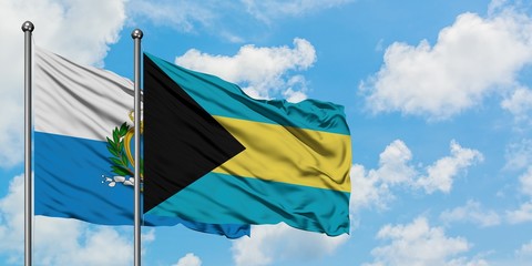 San Marino and Bahamas flag waving in the wind against white cloudy blue sky together. Diplomacy concept, international relations.
