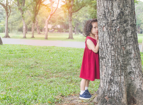 Young asian cute girls playing hide and seek in park, hide behide the tree